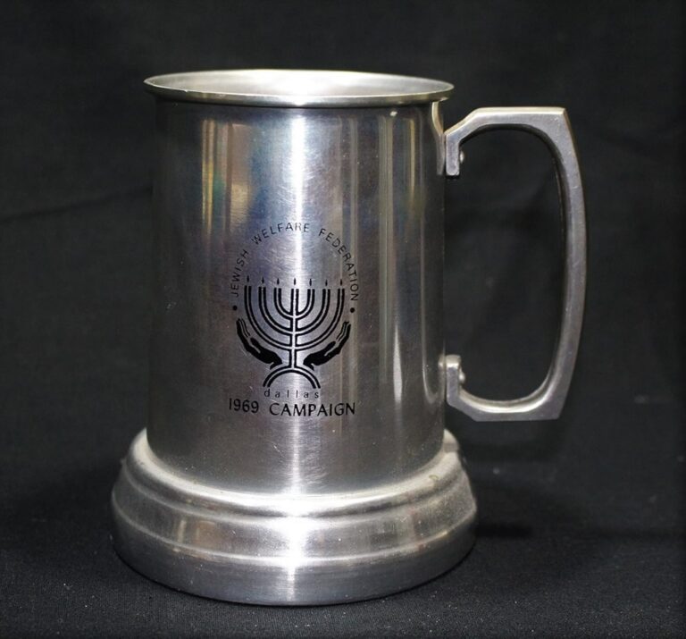 A silver mug with a menorah logo and “Jewish Welfare Federation Dallas 1969 Campaign” on a black background.