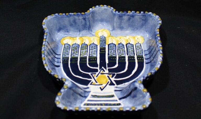 Blue ceramic dish shaped like a dreidel, painted with a menorah and yellow Star of David on a black background.
