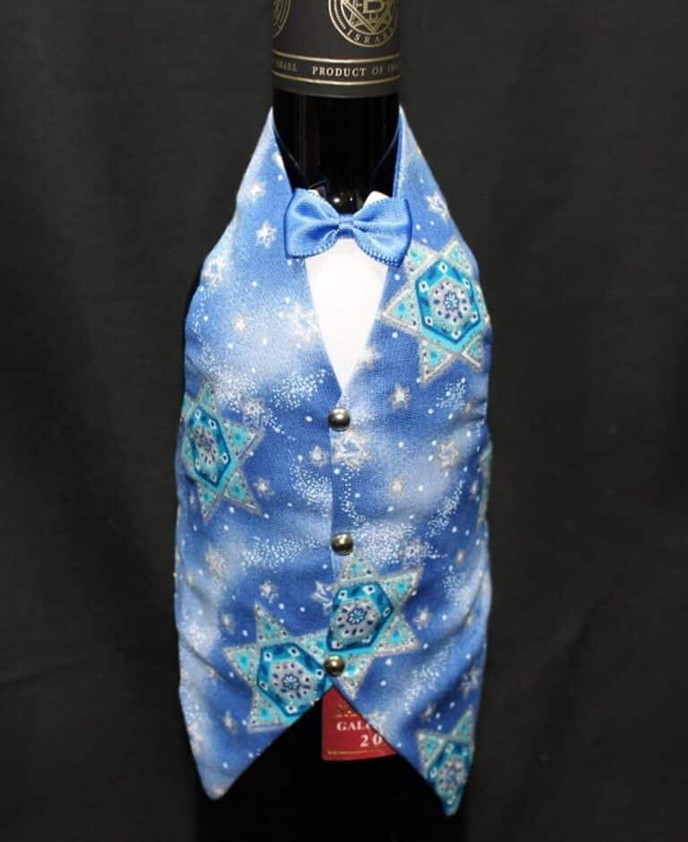 A wine bottle dressed in a blue vest and bowtie with Star of David patterns on a black background.