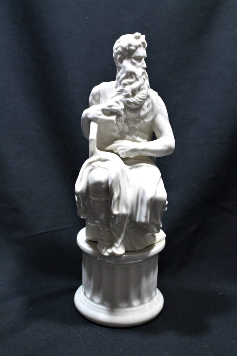 White statue of a bearded man seated on a pedestal, draped in robes, against a black background.