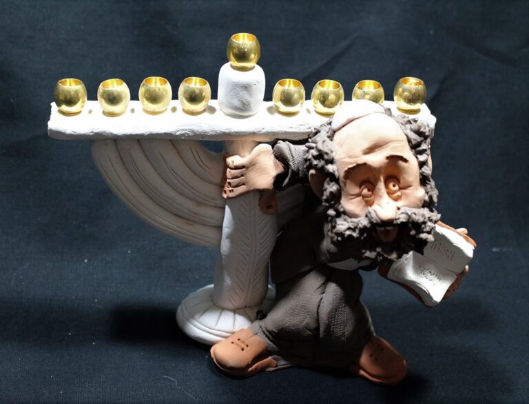 Clay figurine of a man holding a large menorah with lit candles, set against a black background.