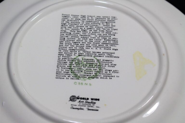 The back of a commemorative plate with printed text about Forest Avenue High School and a green World Wide Art Studios logo.
