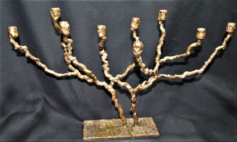 Brass menorah with seven textured, twisted branches on a rectangular base, set against a black background.