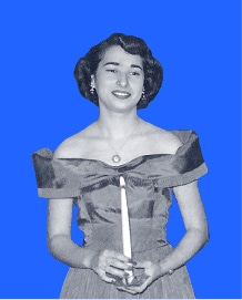 Woman in an off-shoulder dress holds a candle, smiling, posed against a bright blue background.