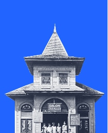 Historic wooden building with a pointed roof, people standing out front, blue background.