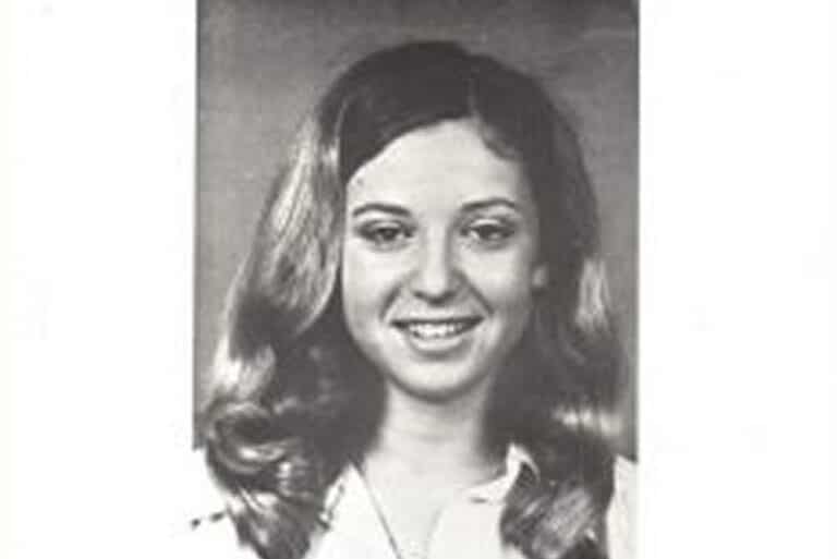Black and white portrait of a young woman with long, wavy hair, smiling at the camera.