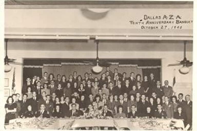 Black-and-white photo of a large group at a banquet, banner reads “Dallas AZA Tenth Anniversary Banquet October 27, 1940.”.
