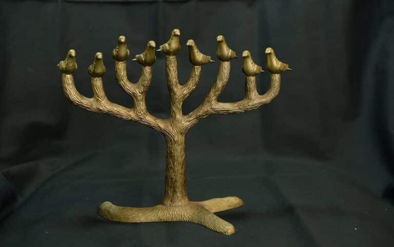 A bronze tree sculpture with nine birds perched on its branches, set against a dark background.
