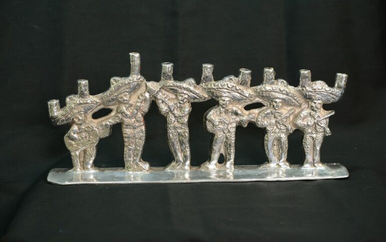 Silver candelabra shaped like six musicians wearing sombreros, each holding an instrument, on a black background.