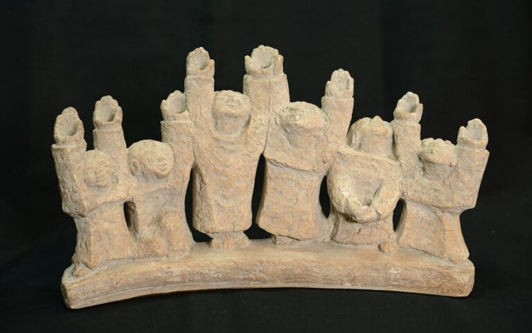 Clay figurines with raised arms stand side by side on a curved base, all set against a black background.