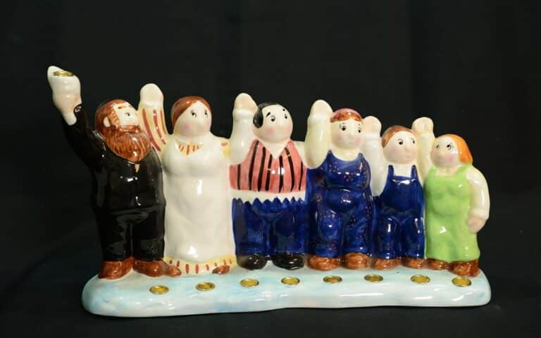Ceramic figurines of seven people standing in a row, each raising one arm, on a blue base with gold circles.