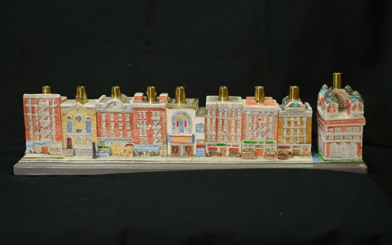A menorah shaped like a row of colorful, detailed buildings against a plain black background.