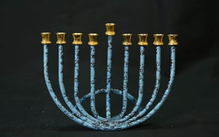 A blue nine-branched menorah with gold-colored candle holders against a black background.