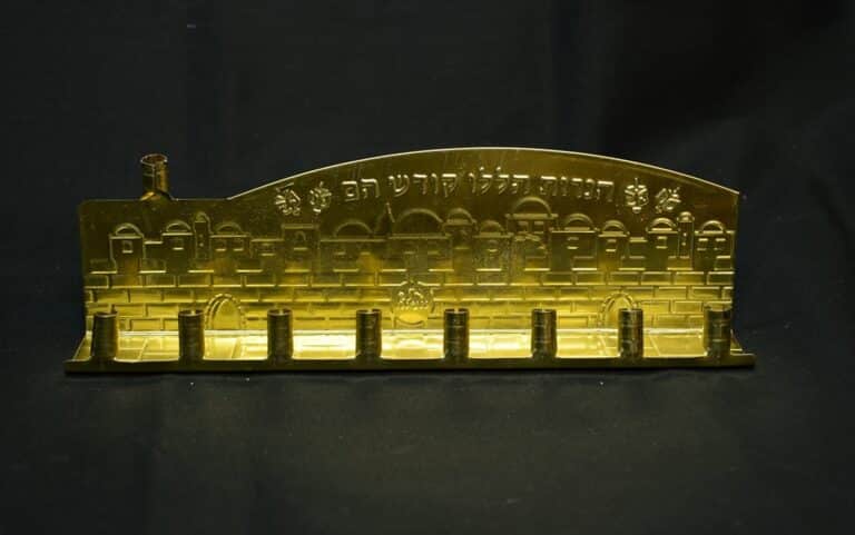 Gold menorah with Western Wall design and Hebrew text, set against a black background.