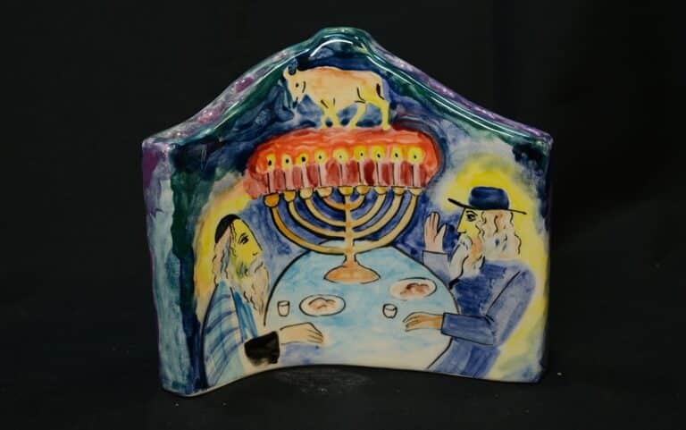 Ceramic art shows two people at a table with food, under a menorah topped by an animal, against a dark background.