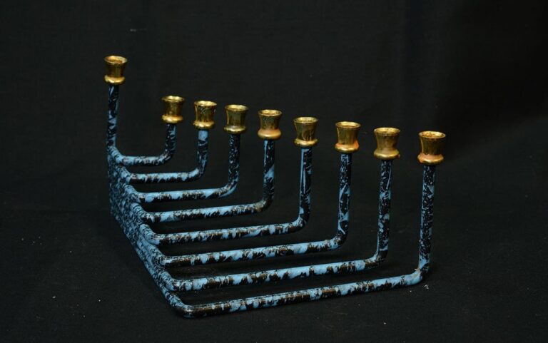 A blue-and-black menorah with nine gold candle holders against a black background.