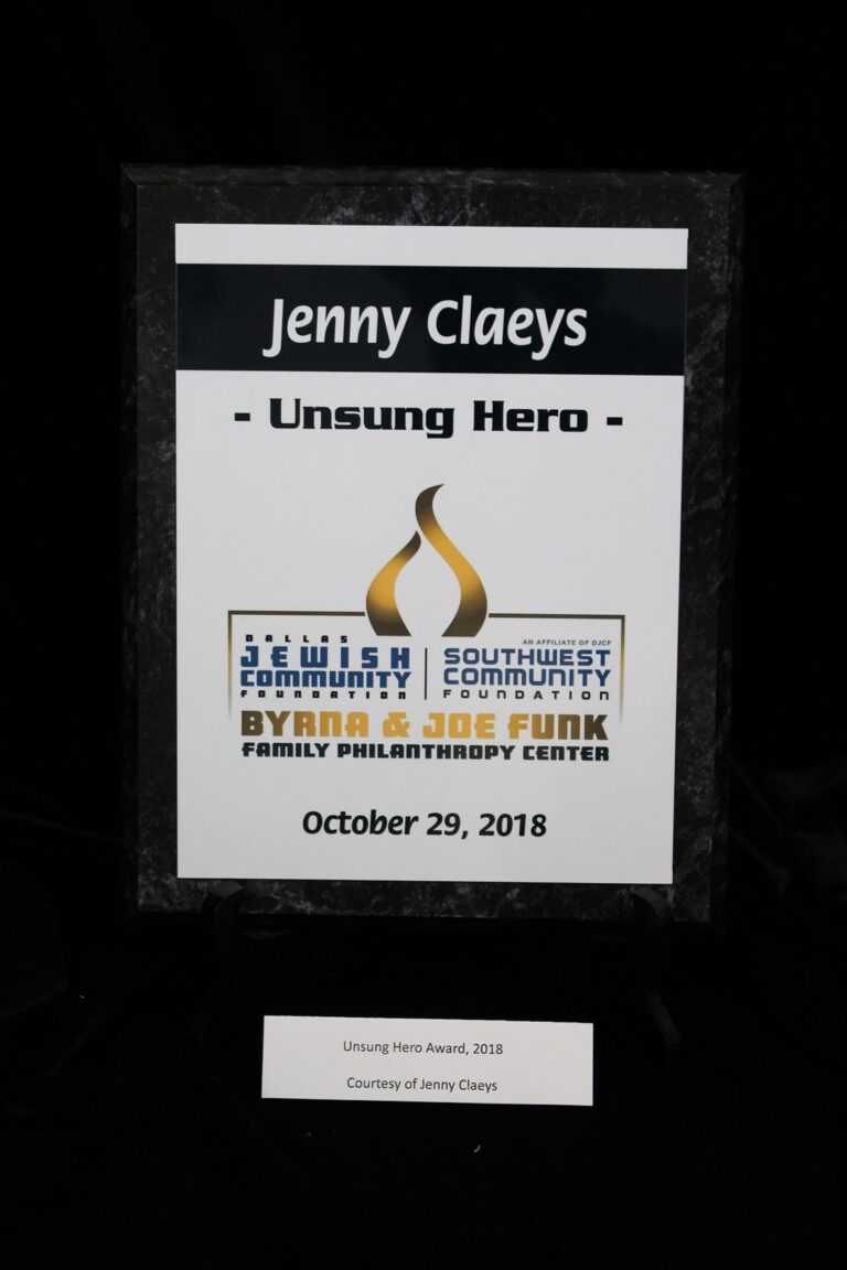 Plaque reading “Jenny Claeys - Unsung Hero” with logos and date October 29, 2018, on a black background.