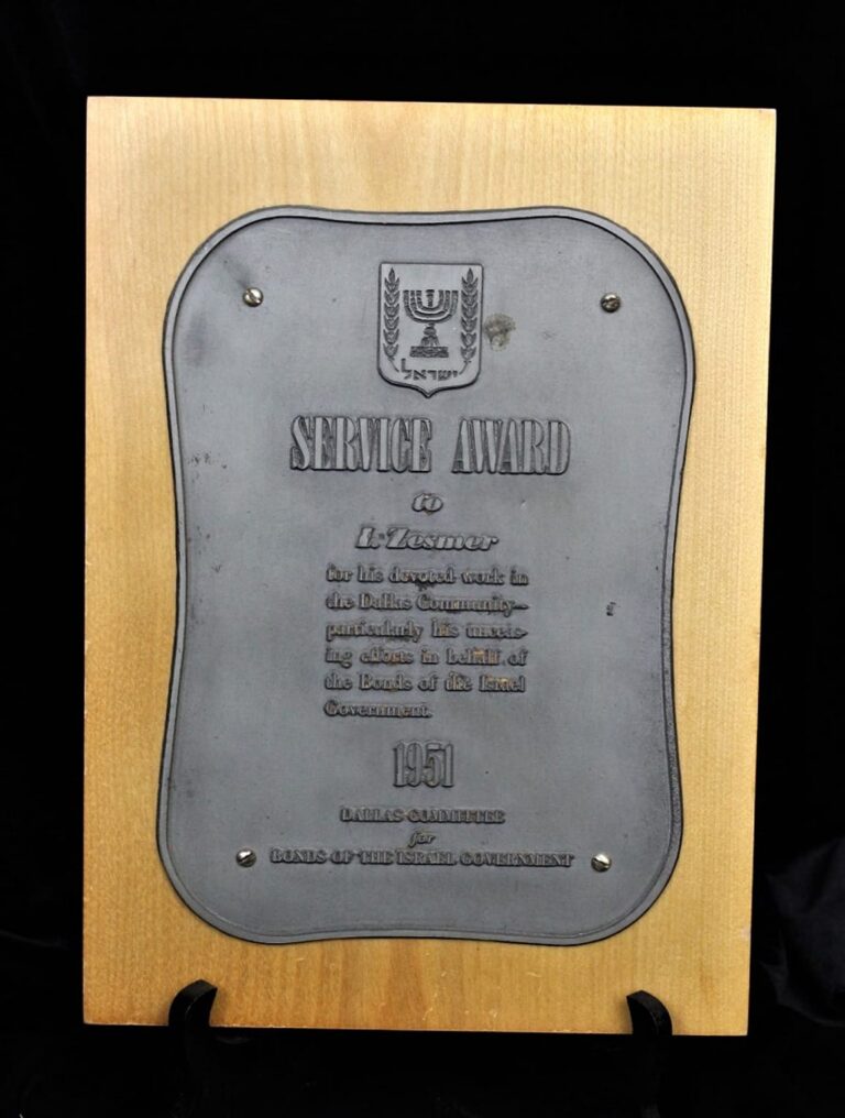 A wooden plaque with a metal plate displaying a “Service Award” and text, featuring a menorah emblem at the top.