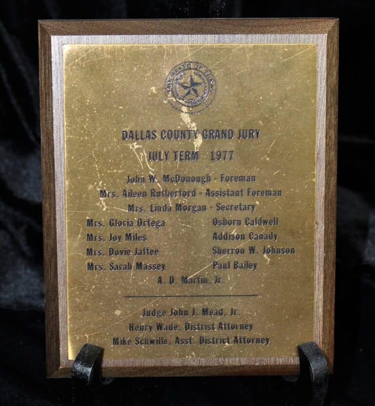 A wooden plaque with engraved names for the Dallas County Grand Jury, July Term 1977, listing members and officials.