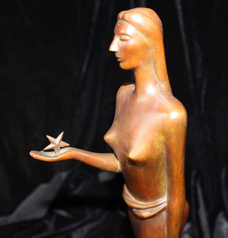 Bronze statue of a woman holding a star in her open hand, set against a black background.