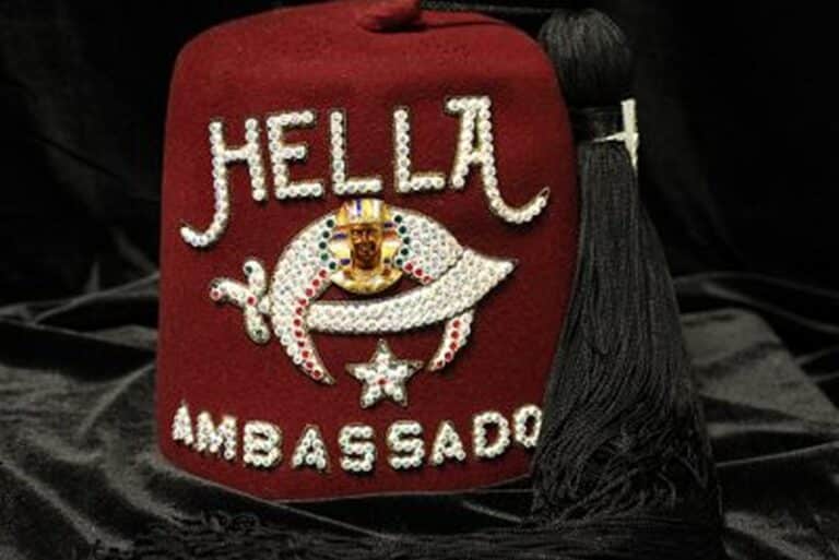 A maroon fez with “HELLA AMBASSADOR” and jeweled designs, including an eye and a star, with a black tassel.