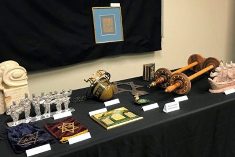A display of various Jewish ceremonial objects, books, and decorations arranged on a black tablecloth.