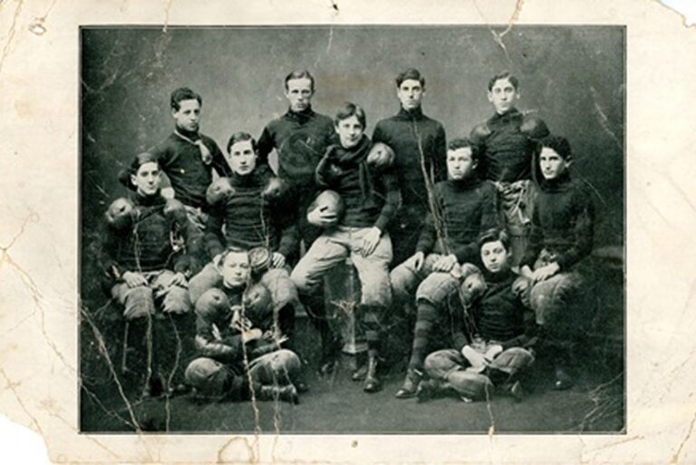 Vintage photo of a football team in old uniforms, eleven players pose seated and standing, facing the camera.