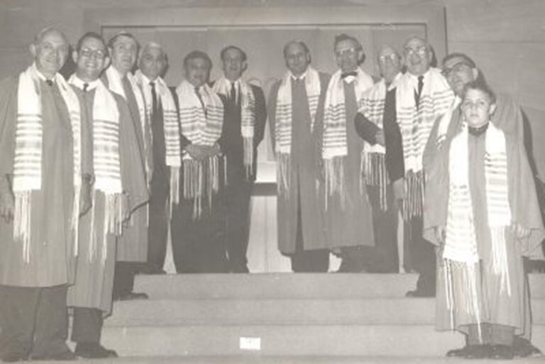 Black and white photo of a group of men and a boy in robes and scarves, standing on steps, facing the camera.