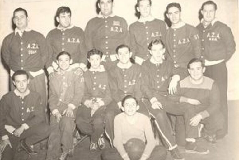 A vintage black and white photo of thirteen young men posing in athletic uniforms labeled “A.Z.A.”.