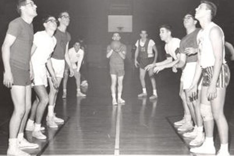 Vintage photo of two basketball teams facing off at center court, ready for the ball to be put in play.