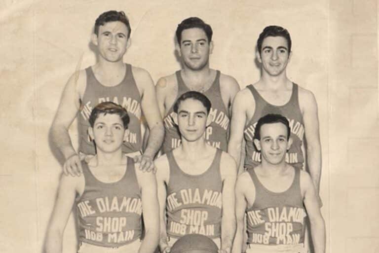 Six men in vintage basketball uniforms pose in two rows, with “The Diamond Shop 1108 Main” on their jerseys.